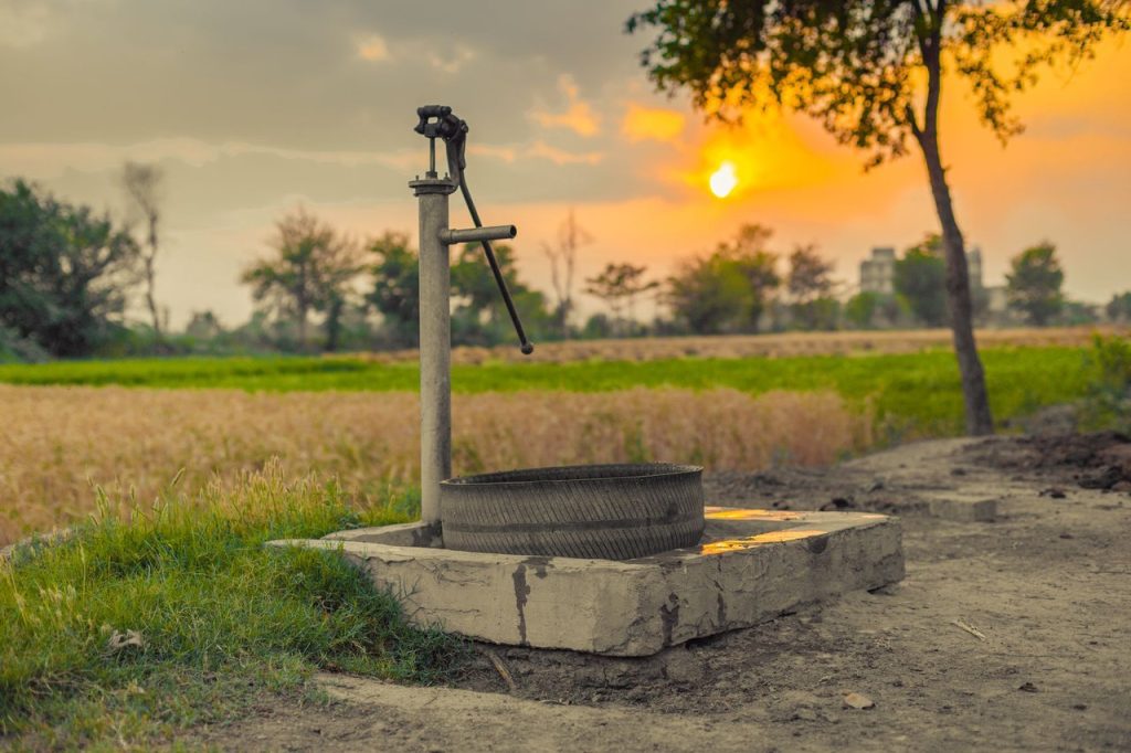 Gestão de poços envolve abastecimento, lavouras e mineração em Mato Grosso Bomba d’água antiga instalada em meio a campos rurais ao entardecer.